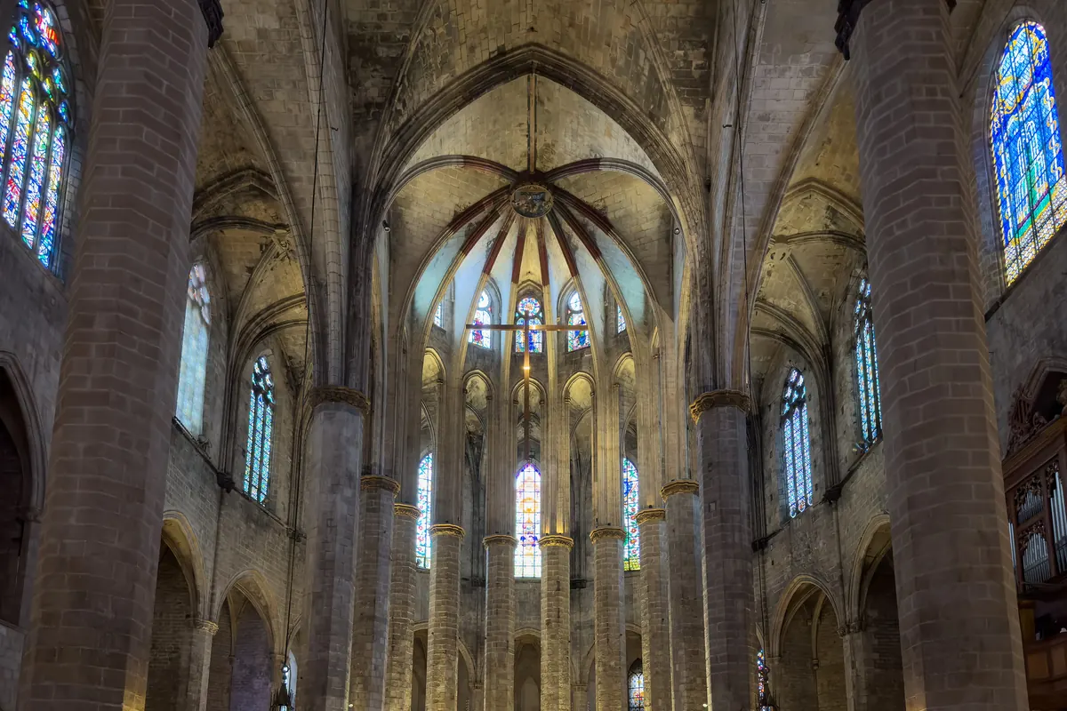 Uvnitř barcelonského kostela Santa Maria del Mar se štíhlé kamenné sloupy zvedají k žebrové klenbě s vitrážemi mezi nimi